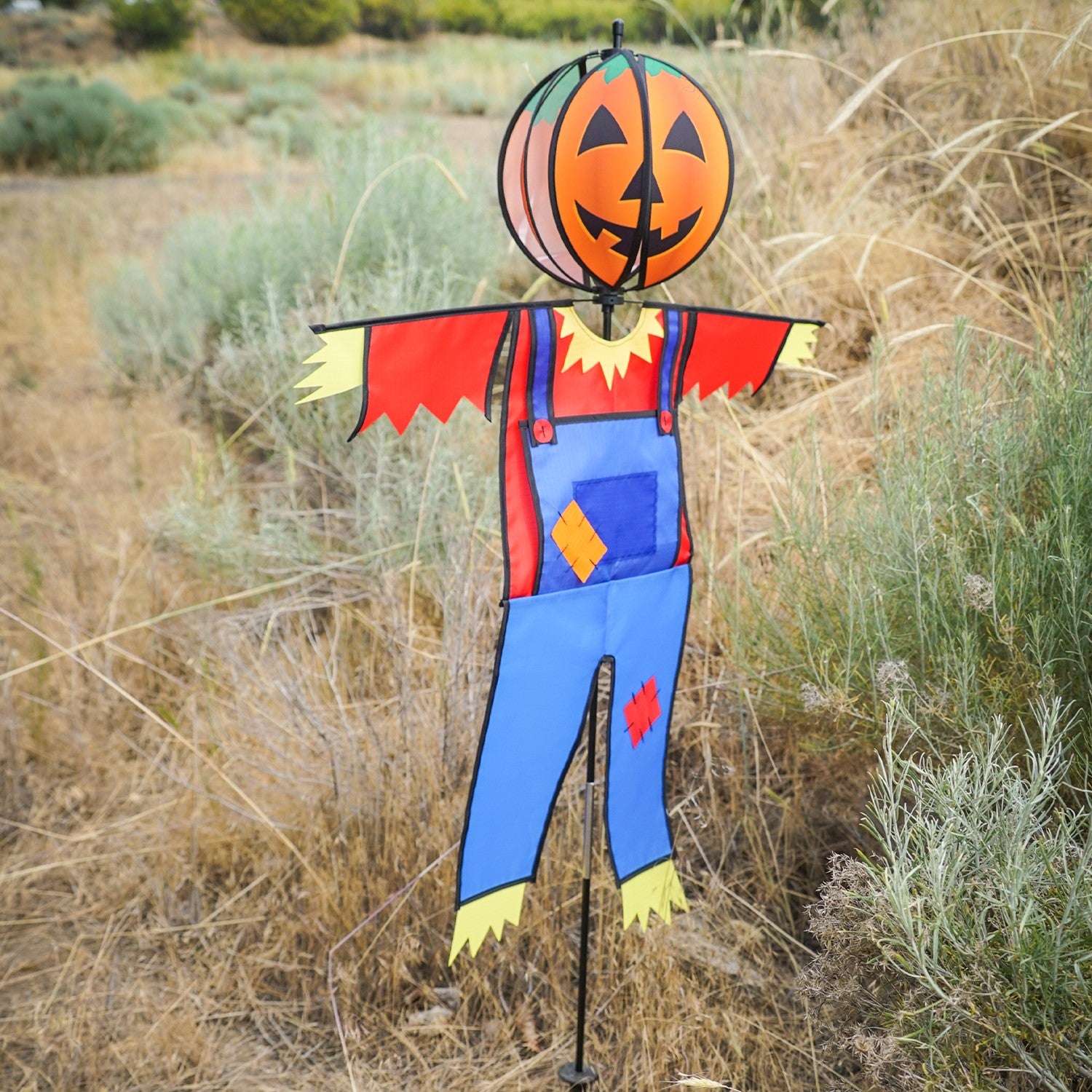 Pumpkin Scarecrow Ground Ball Spinner featuring vibrant pumpkin head and colorful attire, standing tall in a garden setting.