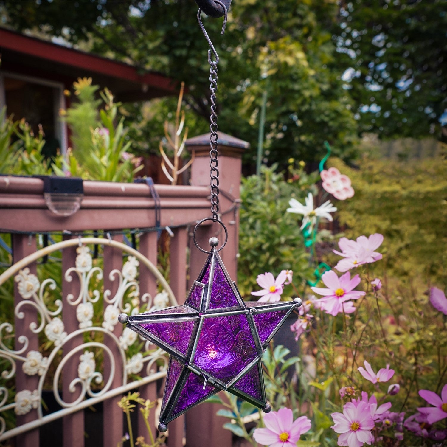 Purple 5-Point Star Hanging Tealight Lantern with intricate glass and metal design, hanging from a chain, creating a warm glow in a cozy setting.