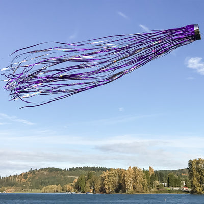 Colorful Purple 51-inch Mylar Windsock with holographic design fluttering in a gentle breeze in a well-kept garden.