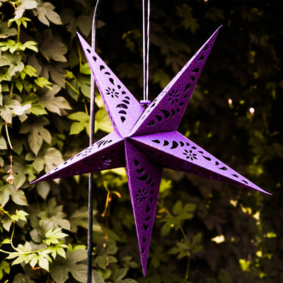 Purple Paper Star Lantern with intricate cutouts and gold accents, hanging indoors, illuminated with fairy lights for a cozy glow.