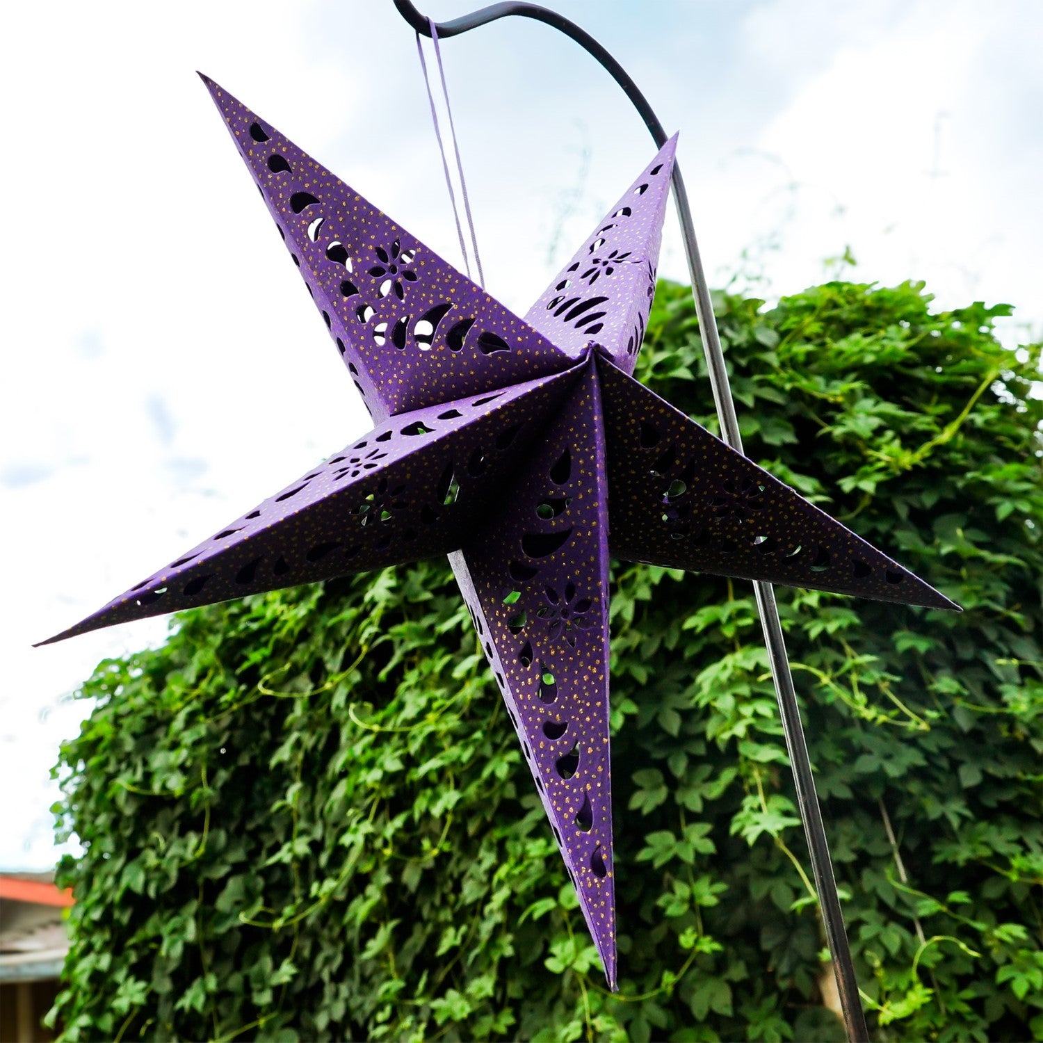 Purple Paper Star Lantern with intricate cutouts and gold accents, hanging indoors, illuminated with fairy lights for a cozy glow.