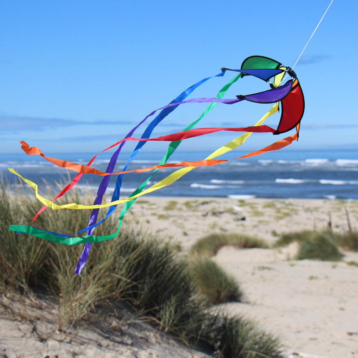 Rainbow 12-inch Orbiter Star with 40-inch streamer tails displayed outdoors, showcasing vibrant colors rotating in the breeze.