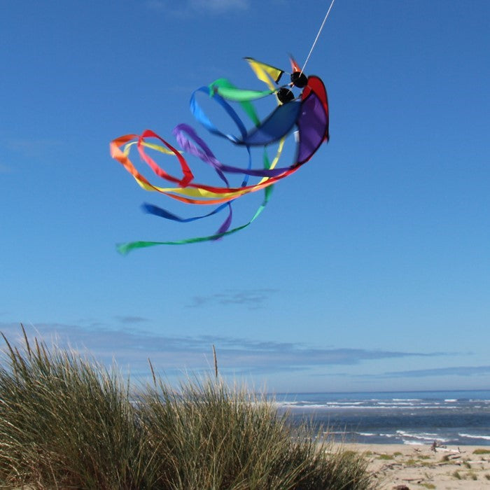 Rainbow 12-inch Orbiter Star with 40-inch streamer tails displayed outdoors, showcasing vibrant colors rotating in the breeze.