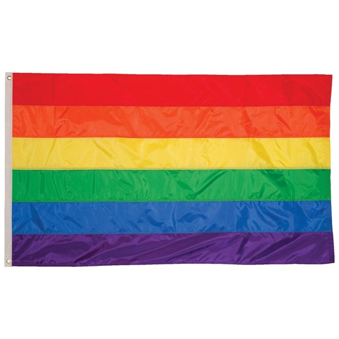 Vibrant Rainbow 4x6 Grommet Flag with bold colors, attached to a flagpole flying against a clear sky, celebrating LGBTQ+ pride and inclusivity.