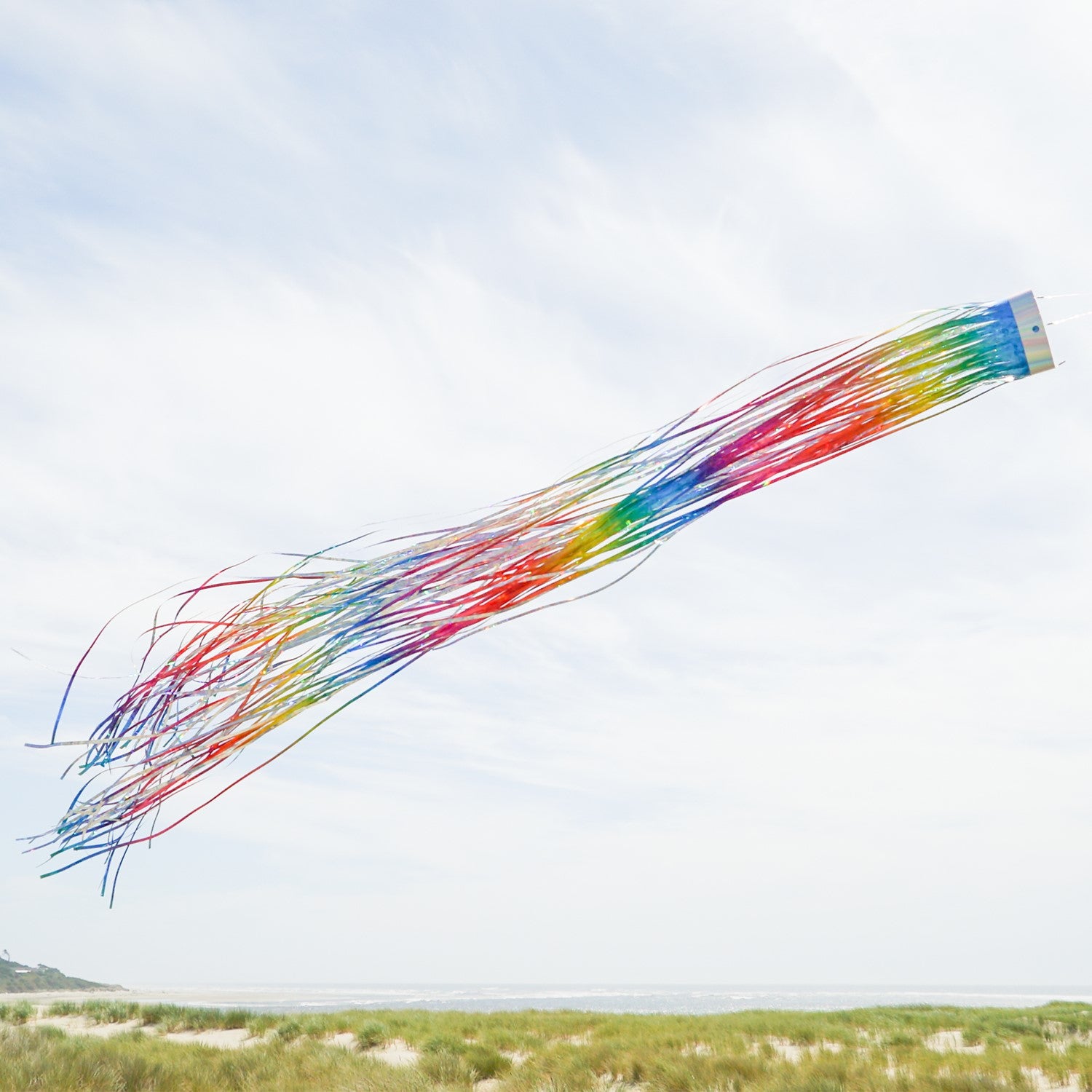 Rainbow 51-inch Mylar windsock fluttering in the breeze, reflecting sunlight with vibrant holographic colors for outdoor decoration.