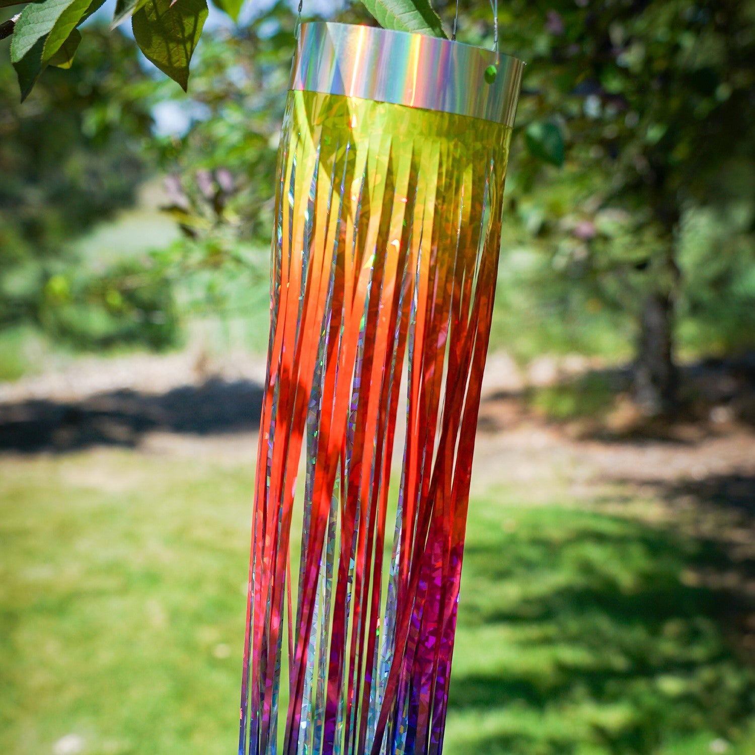 Rainbow 51-inch Mylar windsock fluttering in the breeze, reflecting sunlight with vibrant holographic colors for outdoor decoration.