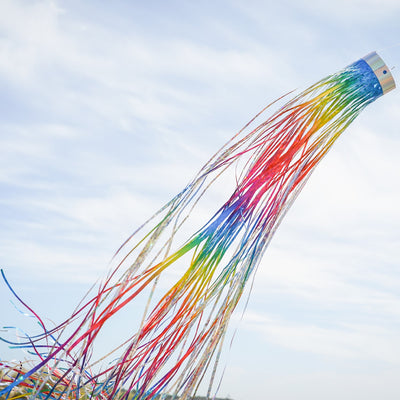 Rainbow 51-inch Mylar windsock fluttering in the breeze, reflecting sunlight with vibrant holographic colors for outdoor decoration.