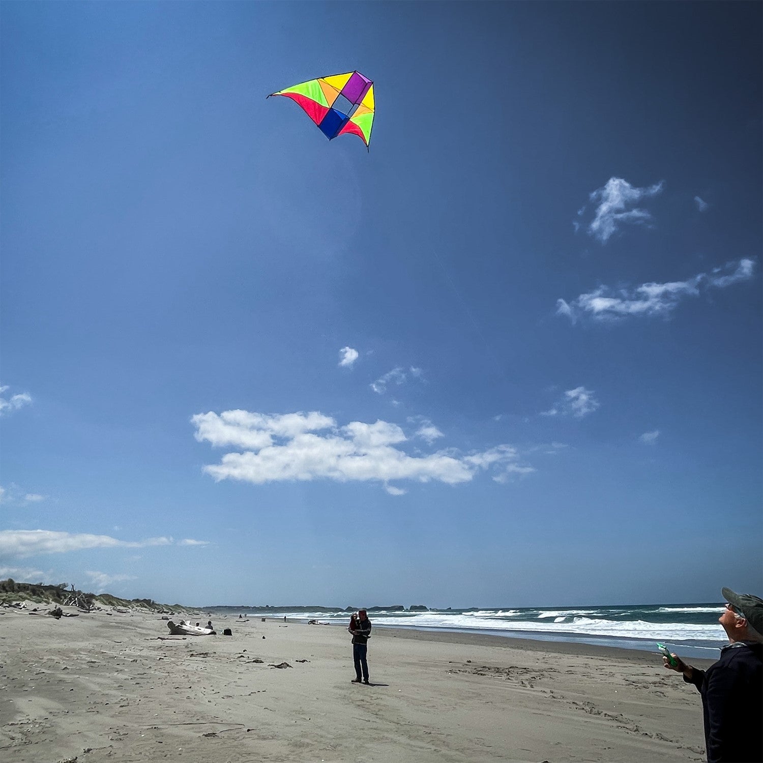 Rainbow 6' Conyne Delta Kite soaring high against a clear blue sky, displaying its bright colors and hybrid design, perfect for outdoor activities.