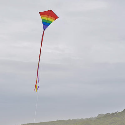 Rainbow Arch 27-Inch Diamond Kite displaying colorful arcs in the sky, ready for flying on a bright day outdoors.
