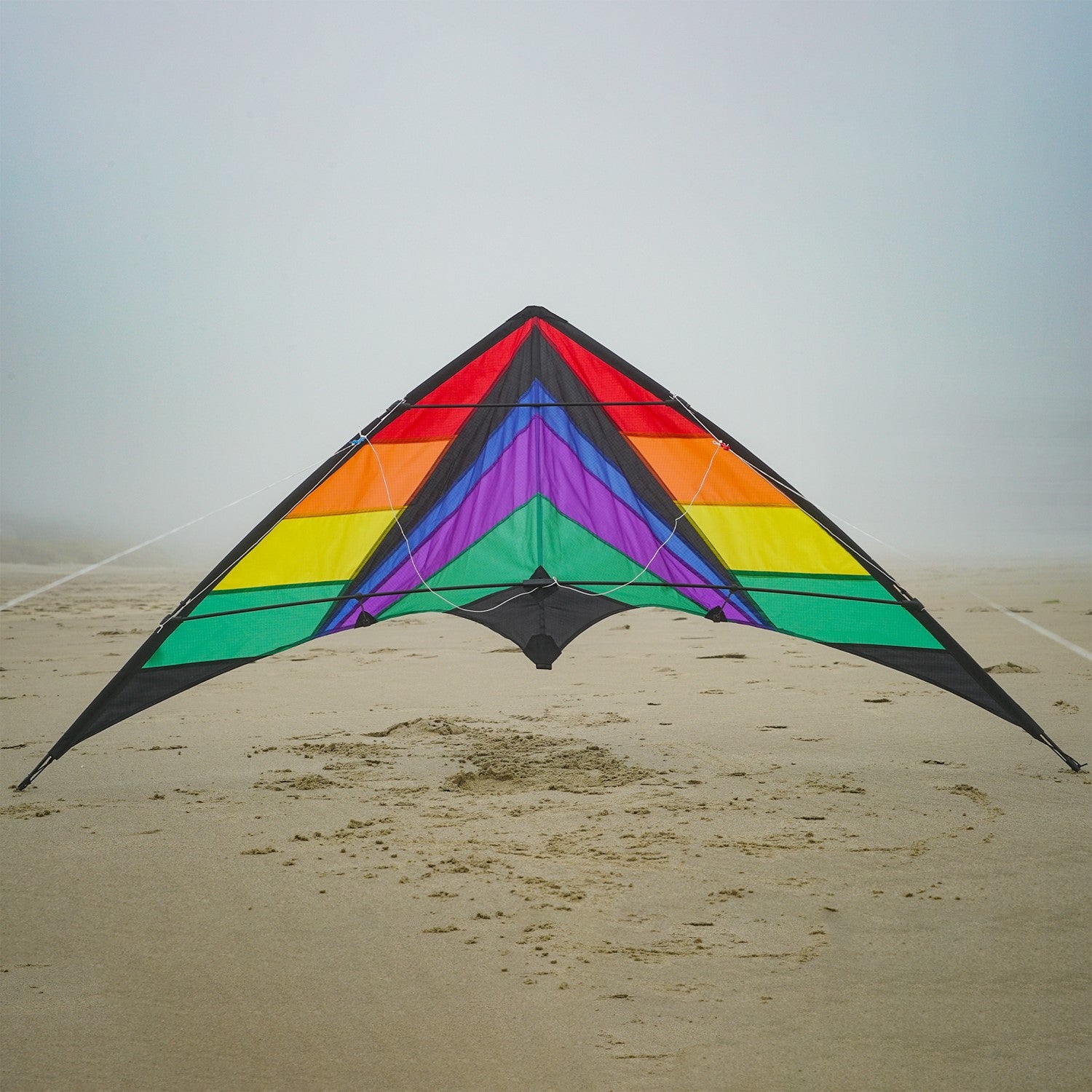 Rainbow Breeze 68" Sport Kite in rainbow color soaring high in a clear blue sky, showcasing its vibrant design and dual control lines.