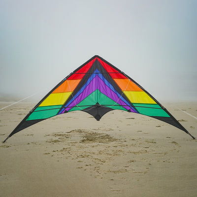 Rainbow Breeze 68" Sport Kite in rainbow color soaring high in a clear blue sky, showcasing its vibrant design and dual control lines.