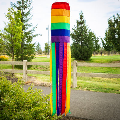 Rainbow Column 40\" windsock featuring bright colors and 12 coordinating tails, hanging in a garden setting on a sunny day.