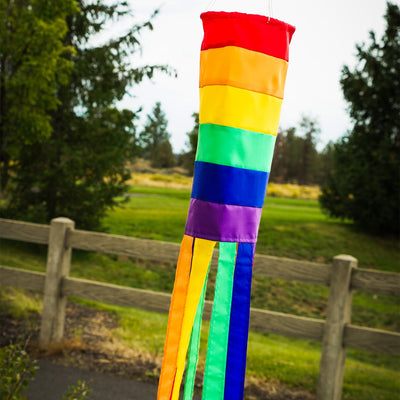 Rainbow Column 40\" windsock featuring bright colors and 12 coordinating tails, hanging in a garden setting on a sunny day.