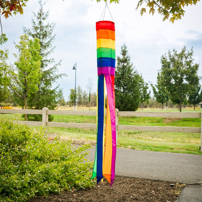 Rainbow Column 50" windsock featuring vibrant rainbow hues and six matching tails, displayed elegantly in a garden setting.