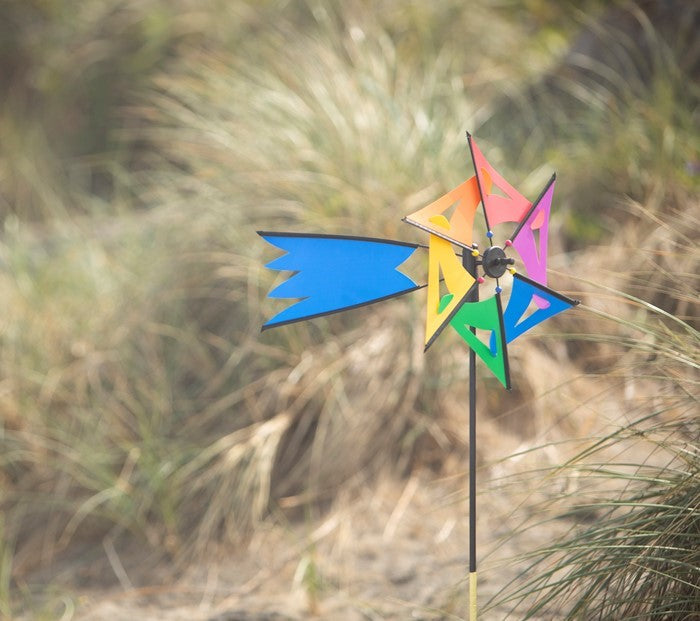 Rainbow Comet Ground Spinner with vibrant colors, displayed in a garden setting, gently spinning in the breeze on a fiberglass rod.