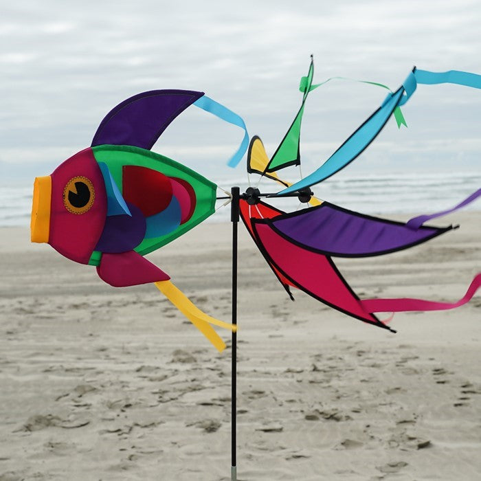 Rainbow Damselfish Spinner featuring vivid rainbow colors in a garden, spinning gracefully atop a fiberglass pole.
