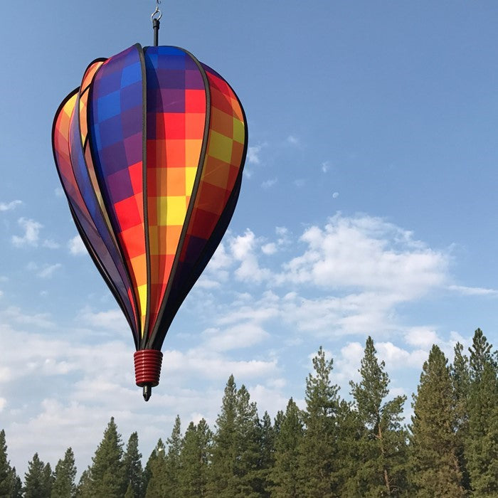 Rainbow Pixel 10-Panel Hot Air Balloon showcased in a garden, spinning in the breeze, showcasing its vibrant pixelated colors.
