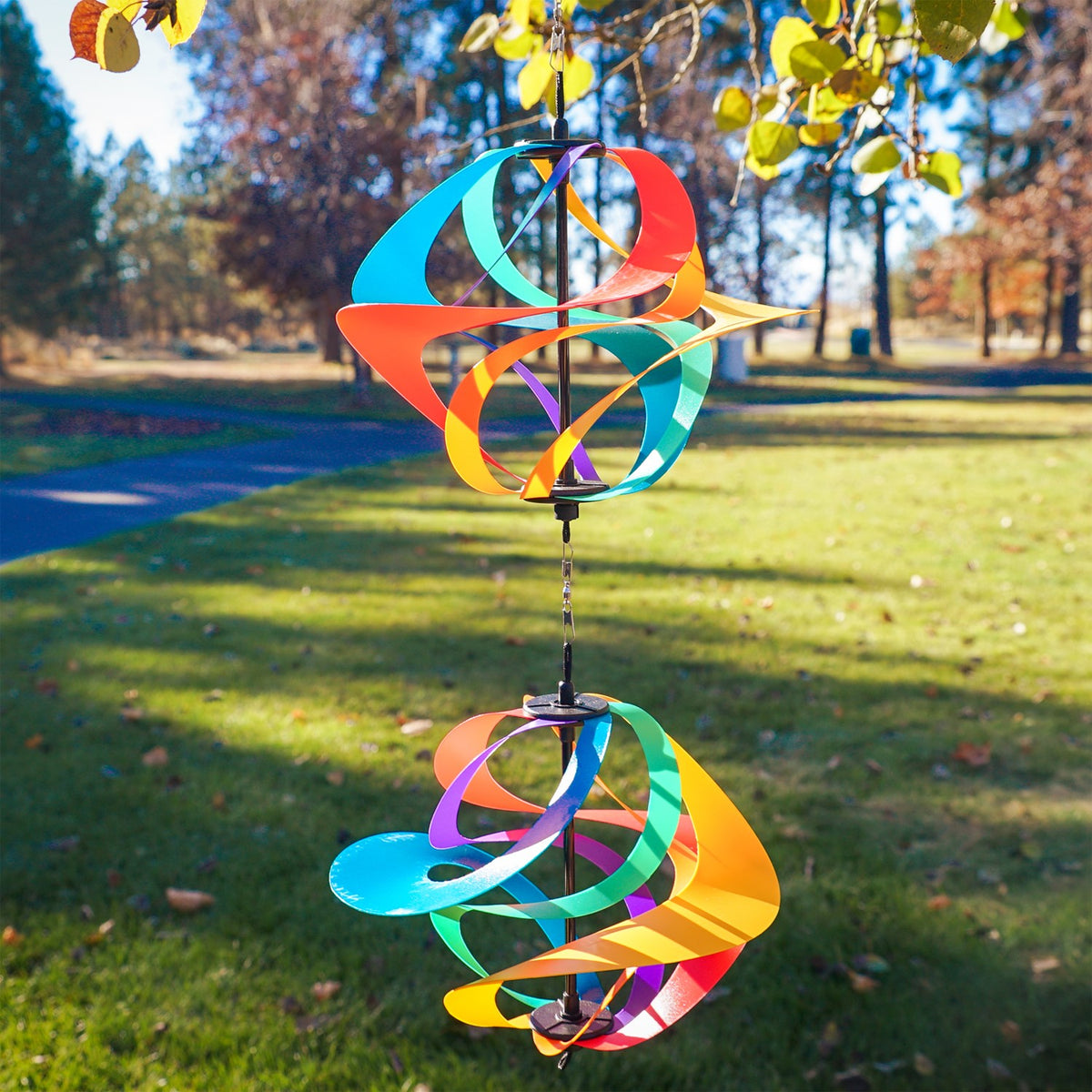 Colorful Rainbow Poly Vortex Double Spinner with interconnected spirals hanging in a garden, catching the breeze beautifully.