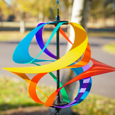Colorful Rainbow Poly Vortex Spinner with six interconnected spirals hanging in a garden, spinning gently in the breeze.