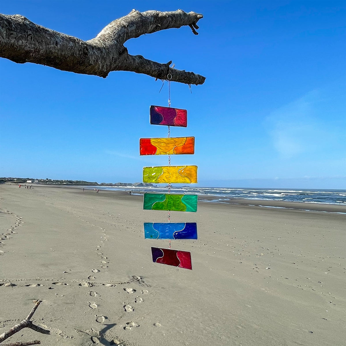 Rainbow Resin Mobile with six colorful translucent blocks hanging outdoors, catching sunlight and swaying gently in the breeze.