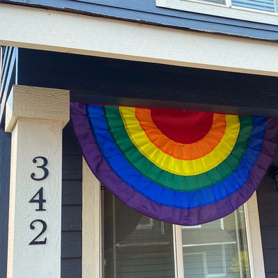 Rainbow Ruffle Bunting with pleated colorful panels displayed outdoors, featuring sturdy brass grommets on a heavy-duty fabric header.