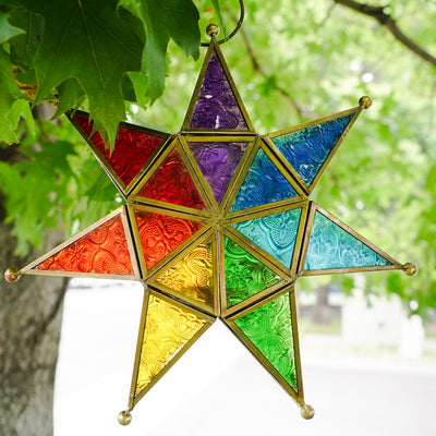 Vibrant Rainbow Seven Point Star Tealight Lantern hanging outdoors, showcasing intricate glass panels and golden metal framing.