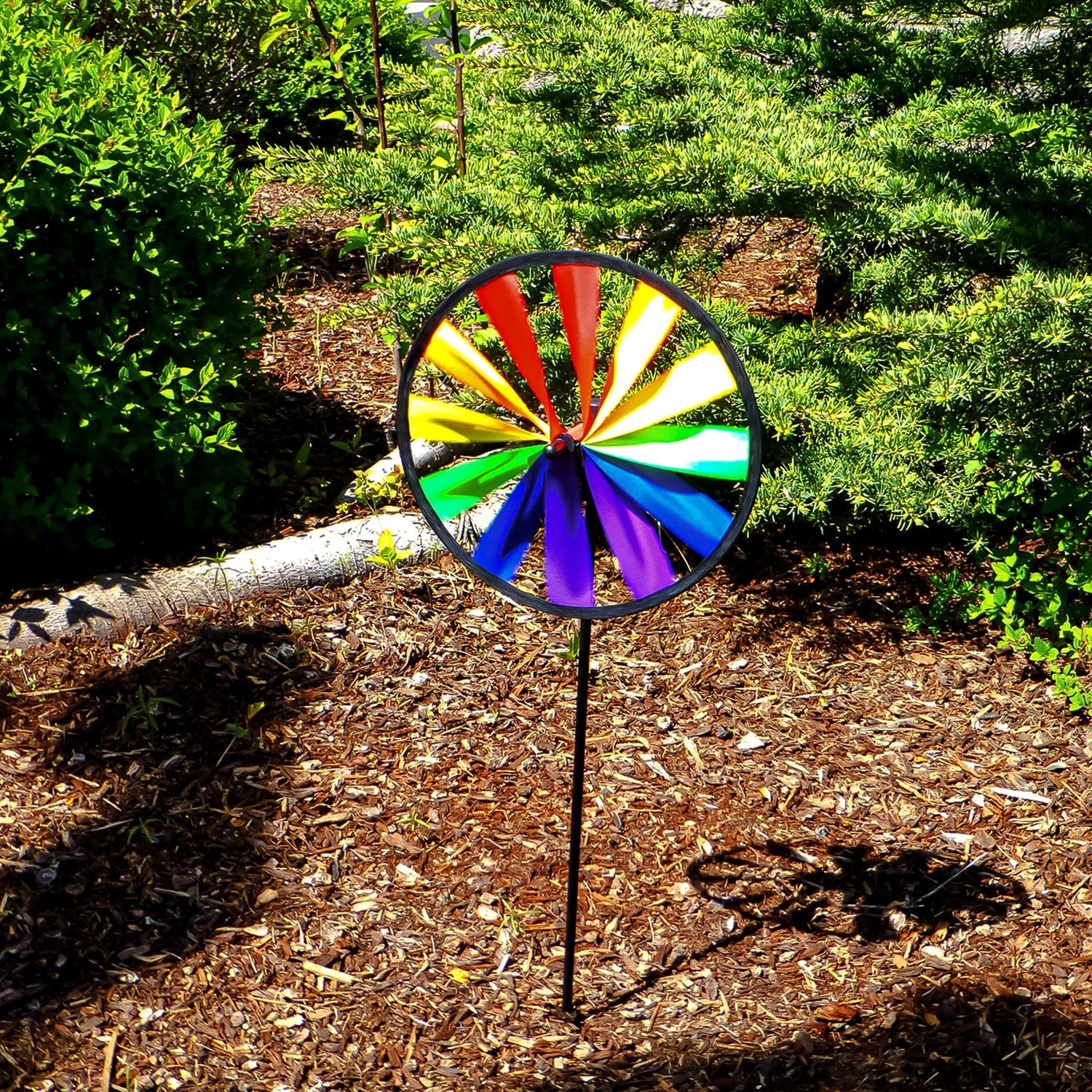 Rainbow Single Wheel Spinner with bright colors spinning in a garden, showcasing its vibrant 8-inch design mounted on a sturdy fiberglass stem.