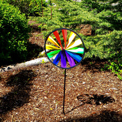 Rainbow Single Wheel Spinner with bright colors spinning in a garden, showcasing its vibrant 8-inch design mounted on a sturdy fiberglass stem.