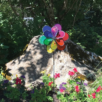 Rainbow Sparkle Windee Wheelz and Flower Spinner featuring double Mylar wheels adorned with colorful petals, spinning in a gentle breeze in a garden setting.