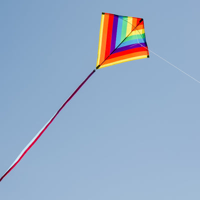 Rainbow Stripe 30 inch diamond kite featuring vibrant rainbow colors and three colorful tails, ready to fly in an outdoor setting.