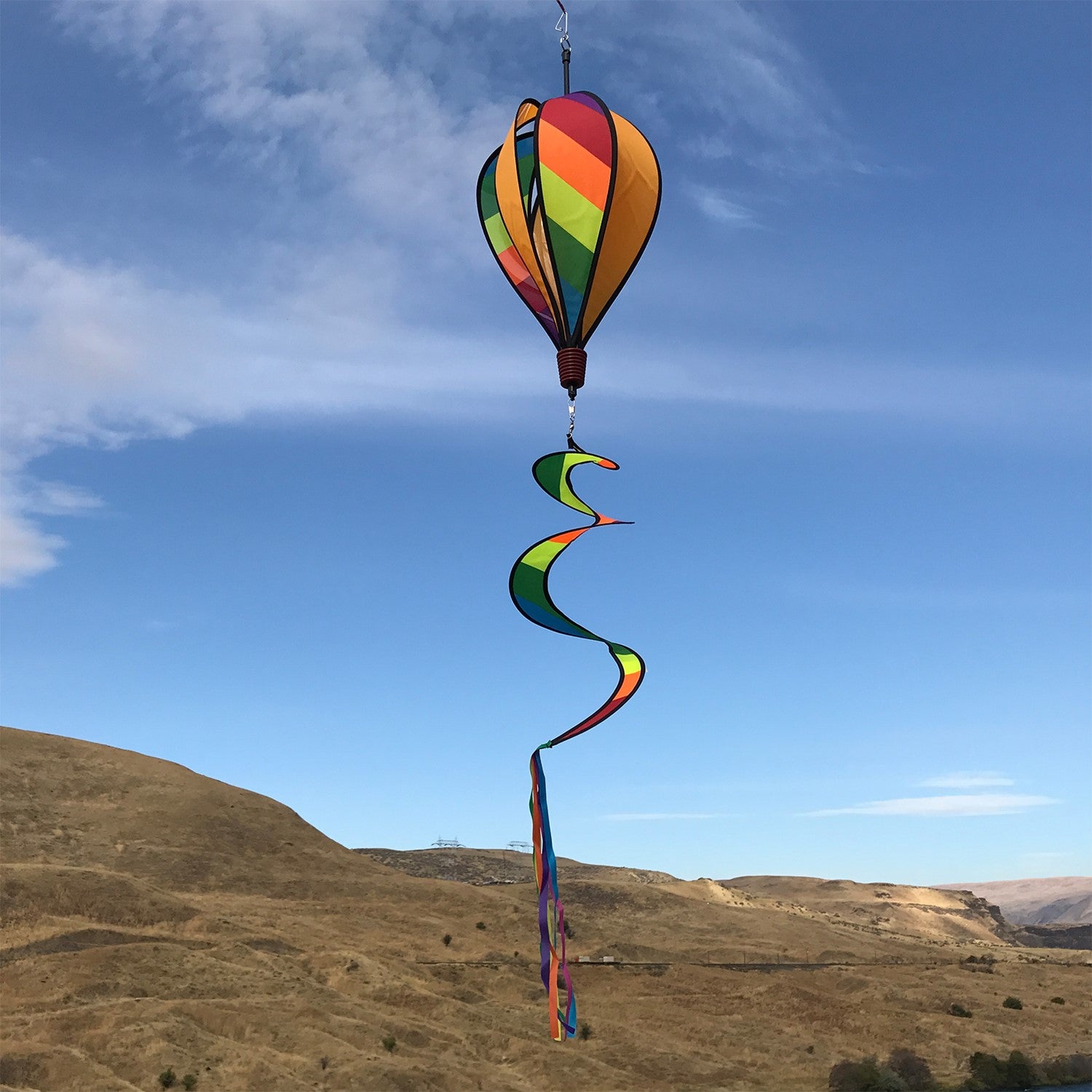 Rainbow Striped Hot Air Balloon spinner in vibrant colors with alternating rainbow and solid striped design, spinning under outdoor sunshine.