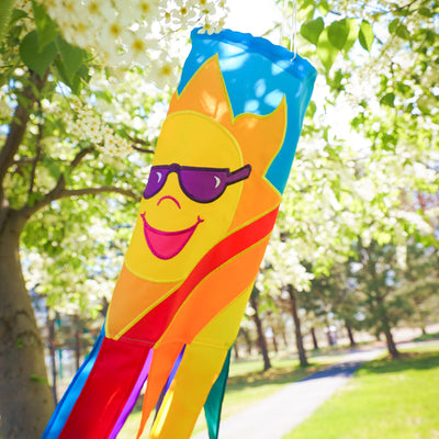 Rainbow Sun 40 inches windsock displaying bright, colorful sun design with eight fluttering tails, hanging in a garden setting.