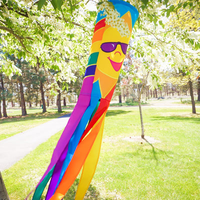 Rainbow Sun 40 inches windsock displaying bright, colorful sun design with eight fluttering tails, hanging in a garden setting.