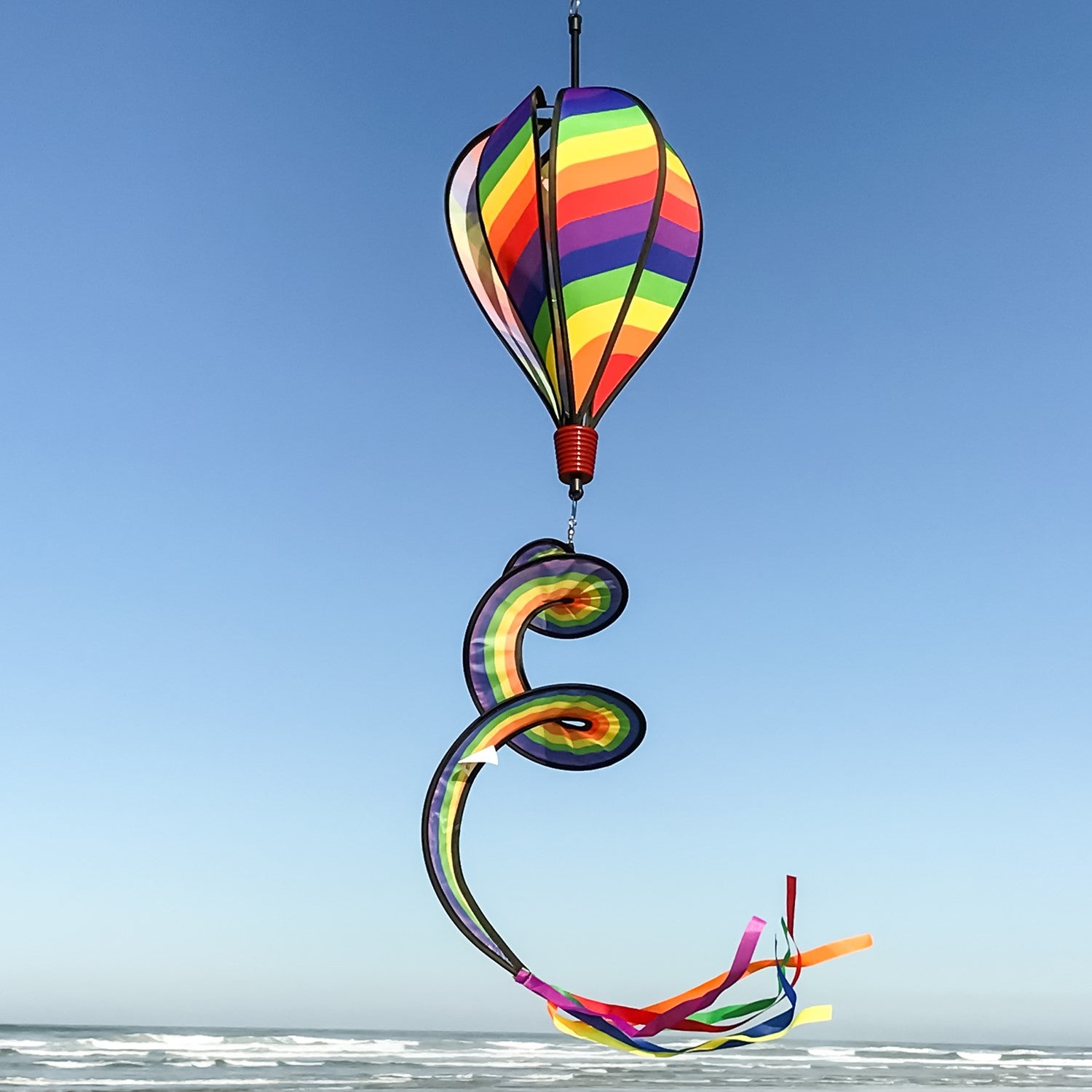 Rainbow Swirl 6-Panel Hot Air Balloon garden spinner in vibrant colors, spinning gently in a light breeze, hanging from a decorative hook.