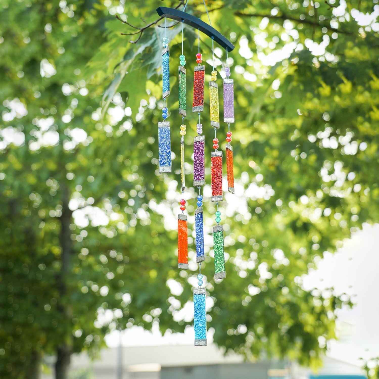 Rainbow Textured Tiered Glass Mobile Wind Chime featuring vibrant glass pieces and beads hanging in sunlight, creating a colorful display outdoors.