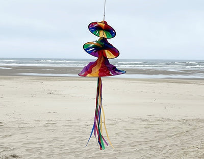 Rainbow Triple Jelly outdoor spinner with three colorful sections spinning in the breeze, showcasing vibrant hues and flowing tails in a garden setting.