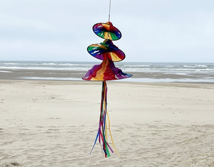 Rainbow Triple Jelly outdoor spinner with three colorful sections spinning in the breeze, showcasing vibrant hues and flowing tails in a garden setting.