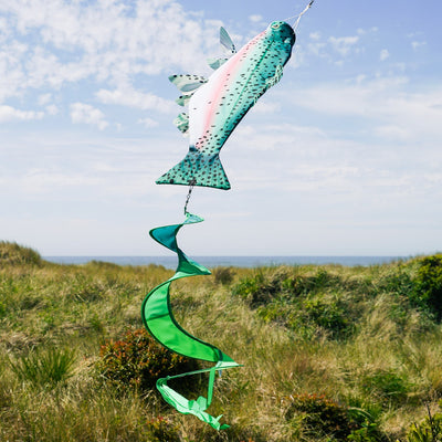 Rainbow Trout Spinner Tail wind sock with vibrant colors and spinning streamer tail, hanging outdoors in a garden setting.