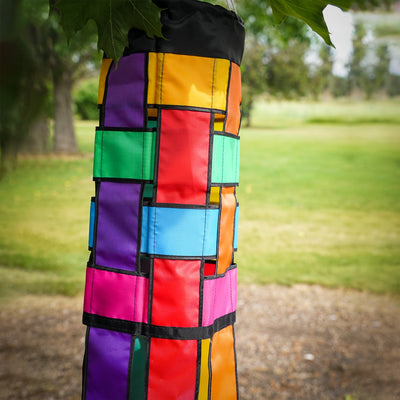 Colorful Rainbow Weave 40" Windsock with black edging and fluttering tails displayed outdoors, showcasing vivid colors against the backdrop.
