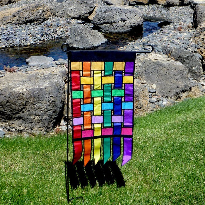 Rainbow Weave Garden Flag Tails featuring interwoven vibrant colors fluttering in the wind, enhancing the outdoor garden decor.