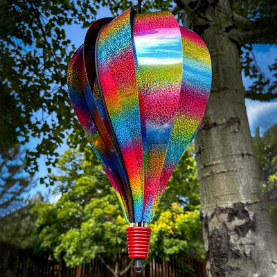 Rainbow Whirl 10-Panel Hot Air Balloon spinner with a sparkling Mylar design, displaying vibrant colors in a garden setting.