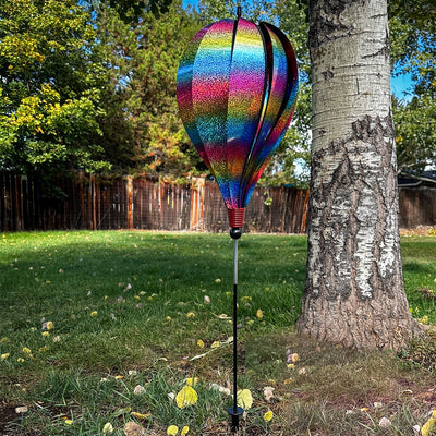 Rainbow Whirl 10-Panel Hot Air Balloon Ground Spinner with vibrant Mylar panels spinning gracefully in an outdoor garden setting.