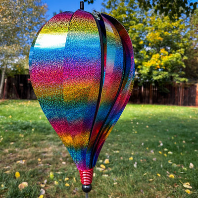 Rainbow Whirl 10-Panel Hot Air Balloon Ground Spinner with vibrant Mylar panels spinning gracefully in an outdoor garden setting.