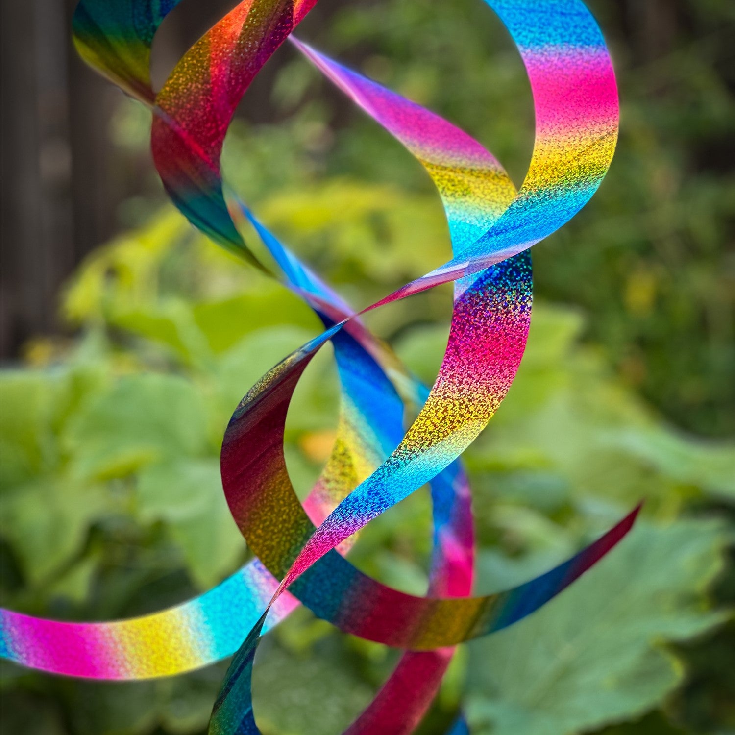 The Rainbow Whirl Mylar Spin Quartet is a stunning hanging decor featuring vibrant mylar curls that shimmer in the sunlight, ideal for outdoor festivities and gardens.