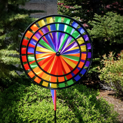 Rainbow Wind Sail Triple Wheel Spinner showcasing three spinning wheels in a rainbow spectrum, set against a clear blue sky with a pivoting pole for wind display.