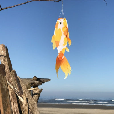 Realistic Yellow Koi 30" Fish Windsock with detailed printed design and flowing tails, displayed in a garden setting, capturing movement in the breeze.