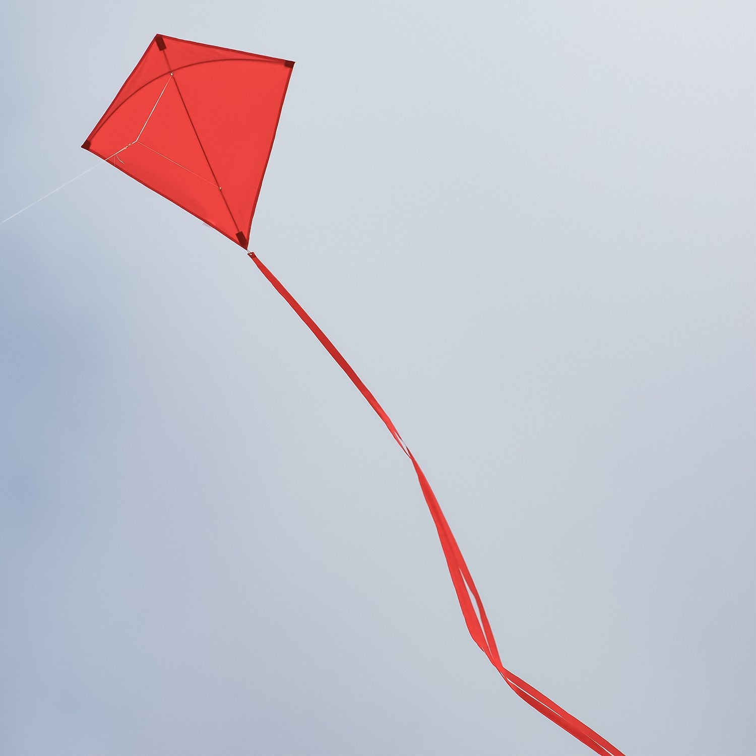 Red Colorfly 30\" Diamond Kite soaring with three colorful tails against a clear blue sky, showcasing its durable design and vibrant color.