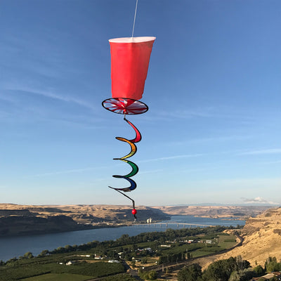 Red Cup 5 O'Clock Spinner features a colorful spinning design resembling a classic red party cup, hanging outdoors in a breezy garden setting.
