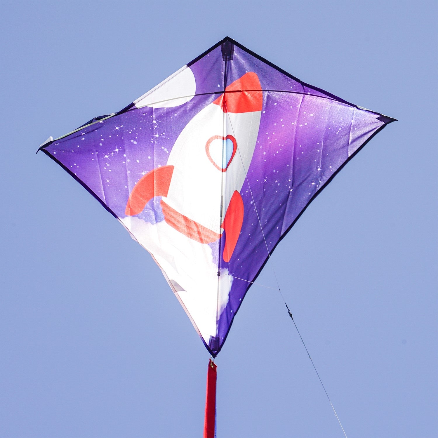 Rocket 30-inch Diamond Kite featuring a colorful rocket ship design with three attached tails, flying high against a blue sky.
