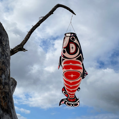 Salmon Totem 48' Fish Windsock featuring vibrant printed patterns hanging outdoors, gently fluttering in the breeze.